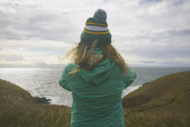 Rear view of woman looking at sea against cloudy sky - CAVF30370