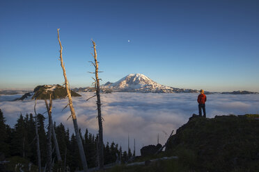 Rückansicht eines männlichen Wanderers, der während des Sonnenaufgangs auf einem Berg vor einer Wolkenlandschaft steht - CAVF30376