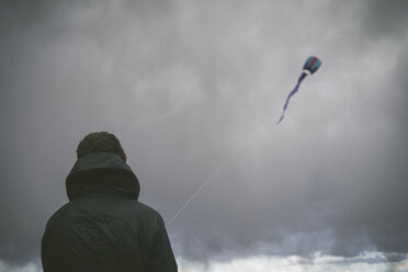 Rückansicht eines Wanderers, der einen Drachen gegen Gewitterwolken steigen lässt - CAVF30386