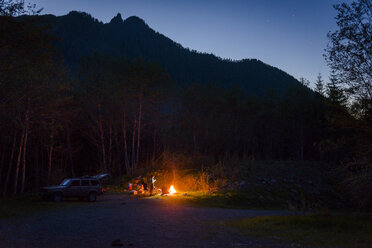 Wanderer beim Zelten am Lagerfeuer gegen die Berge in der Abenddämmerung - CAVF30391