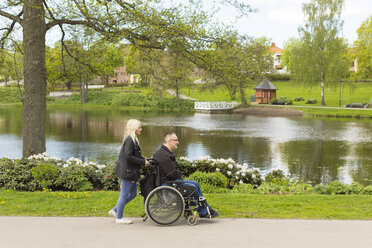 Mann im Rollstuhl mit persönlicher Assistentin im Park - FOLF02302