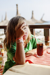 Mädchen sitzt am Tisch und bedeckt ihr Gesicht mit der Hand - FOLF02304