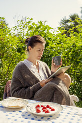 Bild einer Frau, die draußen ein digitales Tablet benutzt - FOLF02329