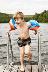 Porträt eines Jungen mit Schwimmflügeln auf einem Steg - FOLF02339