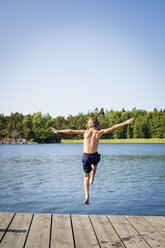 Rückansicht eines Jungen, der vom Steg ins Wasser springt - FOLF02345