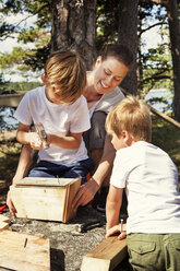 Mother helping sons to build birdhouse - FOLF02349