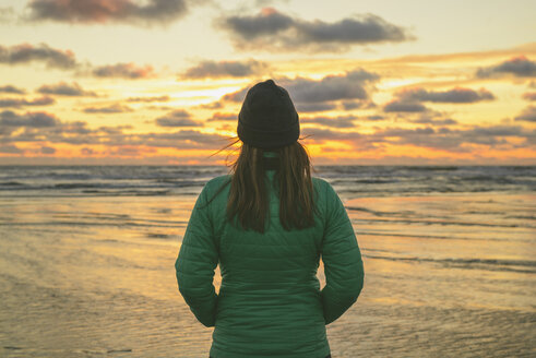 Rückansicht eines Wanderers, der die Aussicht betrachtet, während er am Long Beach gegen den bewölkten Himmel bei Sonnenuntergang steht - CAVF30400