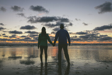 Rückansicht eines sich an den Händen haltenden Paares in Long Beach vor bewölktem Himmel - CAVF30403