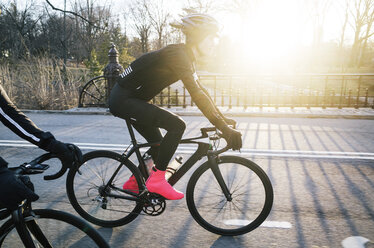 Seitenansicht eines Mannes beim Radfahren auf der Straße an einem sonnigen Tag - CAVF30488