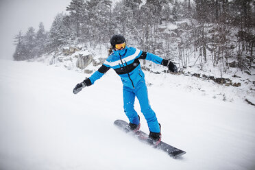 Mann Snowboarding durch Bäume auf schneebedeckten Berg - CAVF30537