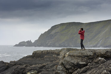 Senior woman standing on rock, looking at view - FOLF02546