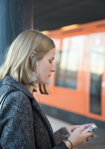 Junge Frau benutzt Smartphone in der Metro Helsinki, lizenzfreies Stockfoto