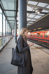 Young woman using smartphone on Helsinki Metro - FOLF02560
