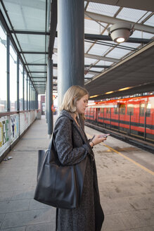 Junge Frau benutzt Smartphone in der Metro Helsinki - FOLF02560