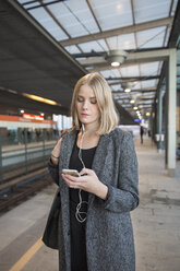 Junge Frau benutzt Smartphone in der Metro Helsinki - FOLF02562