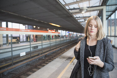 Junge Frau benutzt Smartphone in der Metro Helsinki - FOLF02563
