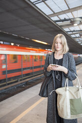 Junge Frau benutzt Smartphone in der Metro Helsinki - FOLF02564