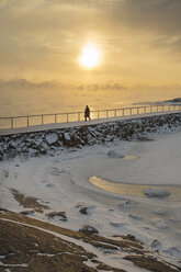 Silhouette of man walking on groyne at sunset - FOLF02568