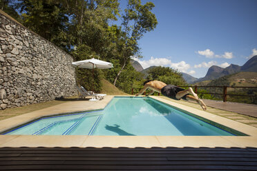 Full length of man jumping in swimming pool at tourist resort - CAVF30593