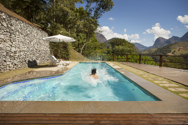 Man swimming at tourist resort with mountains in background - CAVF30596