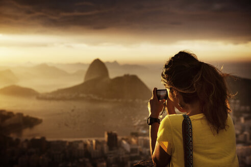 Rückansicht einer Frau, die die Guanabara-Bucht bei Sonnenuntergang fotografiert - CAVF30606