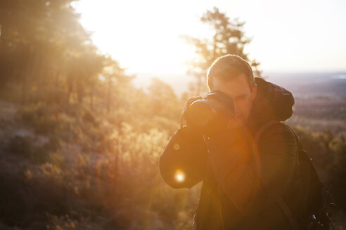 Mann beim Fotografieren gegen den klaren Himmel im Wald an einem sonnigen Tag - CAVF30613