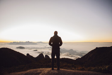 Rear view of man standing on mountain during sunset - CAVF30629