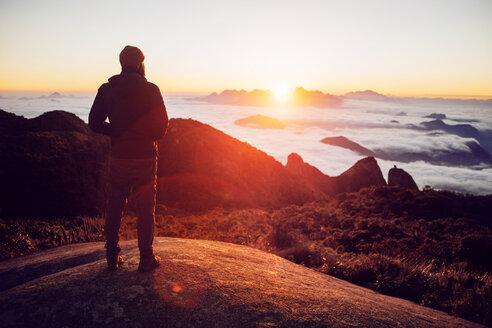 Rückansicht eines Wanderers, der bei Sonnenuntergang auf einem Berg steht - CAVF30631