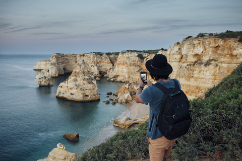 Wanderer, der am Praia da Marinha mit seinem Smartphone Berge am Meer fotografiert, lizenzfreies Stockfoto