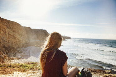 Rear view of woman relaxing at beach on sunny day - CAVF30669