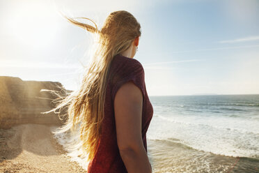 Seitenansicht einer Frau, die am Strand steht und die Aussicht betrachtet, an einem sonnigen Tag - CAVF30672