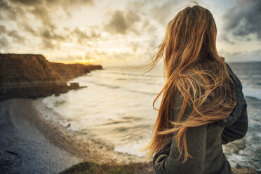 Side view of woman looking at view while standing at beach - CAVF30682