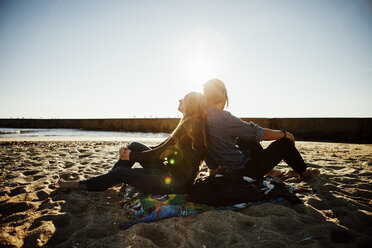 Seitenansicht eines am Strand sitzenden Paares gegen den klaren Himmel - CAVF30692