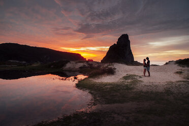 Romantic couple standing on sand against sky during sunset - CAVF30693