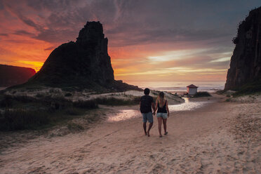 Rückansicht eines Paares, das bei Sonnenuntergang auf Sand gegen den Himmel läuft - CAVF30694