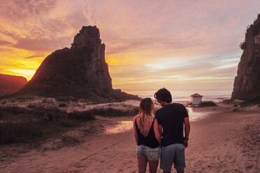 Rear view of couple standing on sand at beach during sunset - CAVF30695