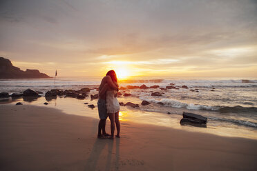 Couple embracing at beach against clear sky during sunset - CAVF30698