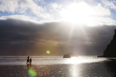 Mother and daughter walking in sea against cloudy sky - CAVF30725