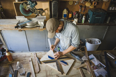 Hochformatige Ansicht eines Künstlers, der Holzkunst an einer Werkbank in einer Werkstatt herstellt - CAVF30743