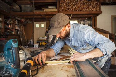 Serious craftsperson measuring wooden art at workshop - CAVF30751