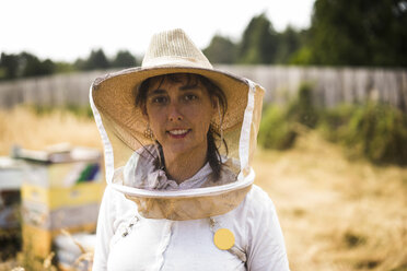Porträt einer Imkerin mit Schutzmaske und Hut auf einem Feld - CAVF30774