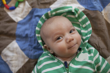 Hohe Winkel Porträt der niedlichen Baby Junge trägt Kapuzen-Shirt, während auf dem Bett zu Hause liegen - CAVF30826