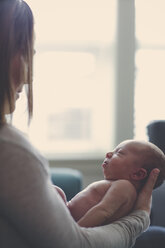 Side view of mother holding baby boy at home - CAVF30829