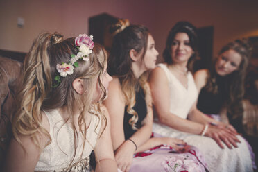 Braut mit Brautjungfern und Blumenmädchen zu Hause sitzend - CAVF30840