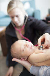 Doctor examining newborn baby boy held by mother - CAVF30856