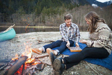 Young couple playing chess at lakeshore - CAVF30873