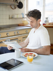 Mann liest Zeitung am Frühstückstisch - FOLF02634