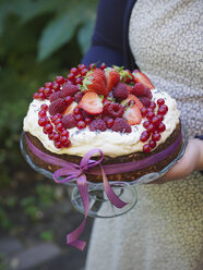 Frau trägt Kuchen mit frischen Beeren in der Hand - FOLF02820