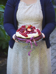 Frau trägt Kuchen mit frischen Beeren in der Hand - FOLF02821