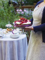 Frau trägt Kuchen mit frischen Beeren in der Hand - FOLF02822
